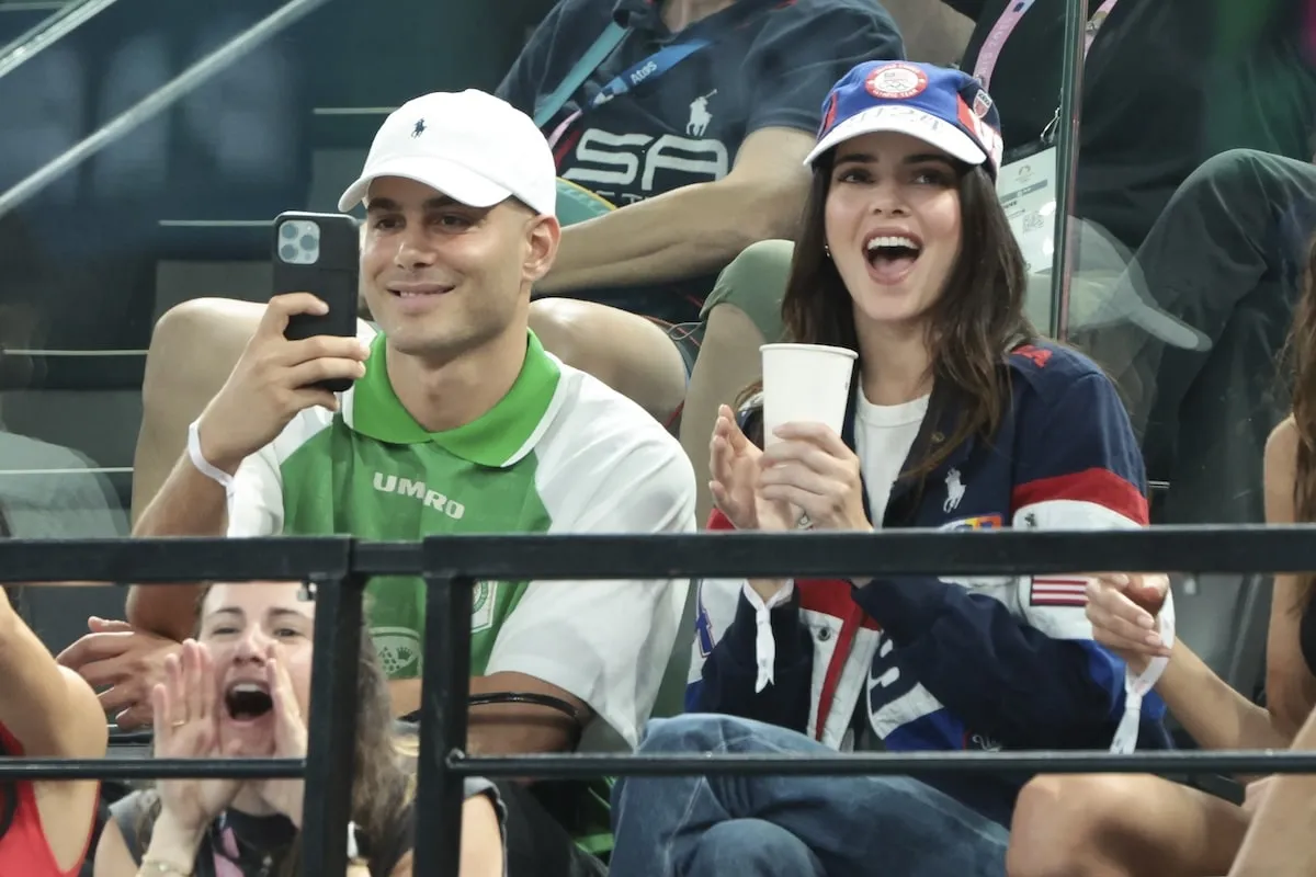 Fai Khadra in a green polo and Kendall Jenner in red white and blue cheer for the U.S. women's gymnastics team at the 2024 Summer Olympics