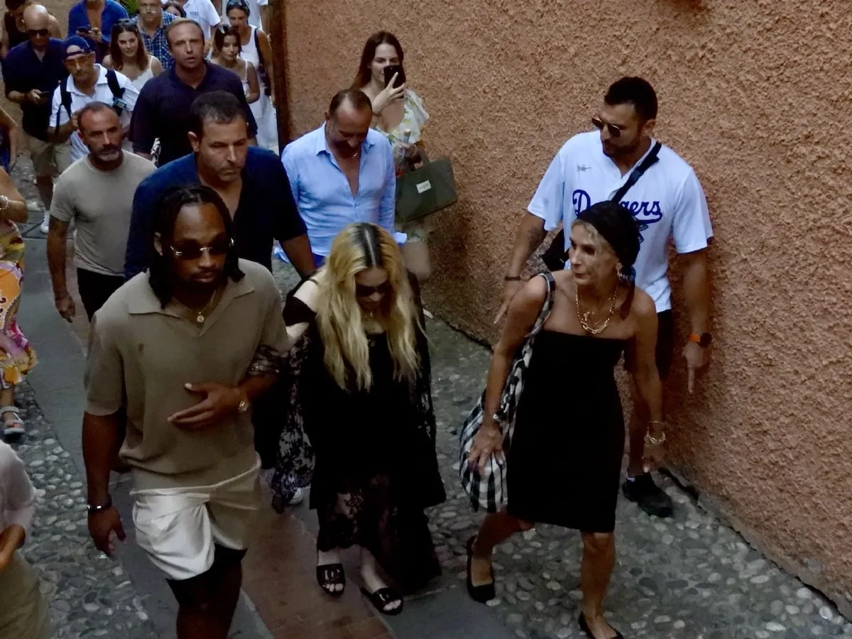 Wearing a black dress and carrying a white lacy umbrella, Madonna walks through Portofino, Italy, with her boyfriend Akeem Morris