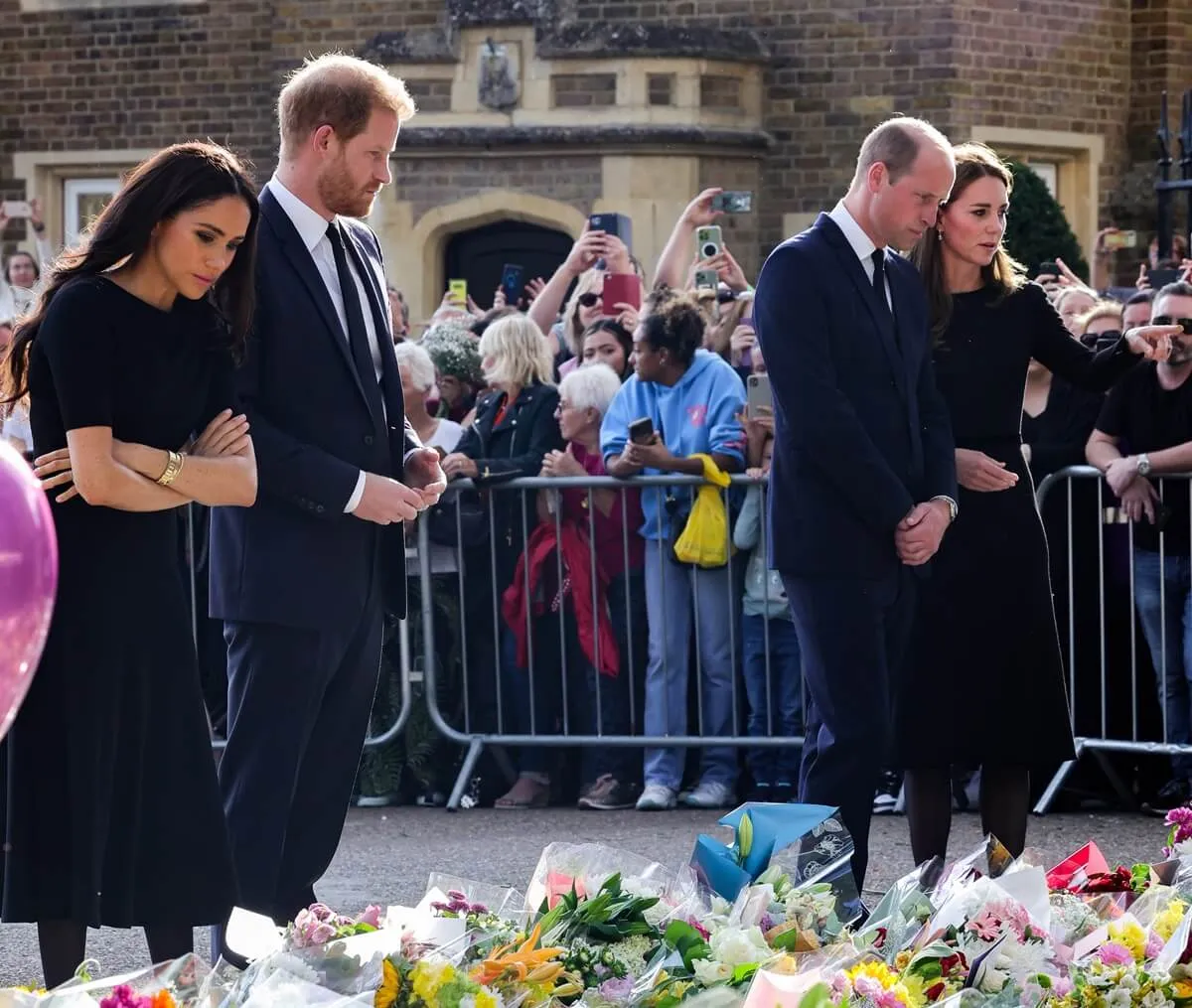 Meghan Markle, Prince Harry, Prince William, and Kate Middleton look at floral tributes laid by members of the public on the Long Walk at Windsor Castle