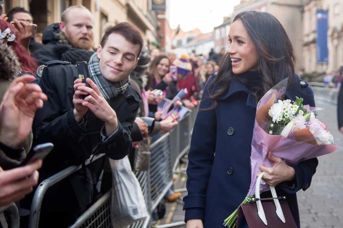 Meghan Markle, who changed her approach to getting dressed after carrying a Strathberry handbag, in 2017, greets crowds.