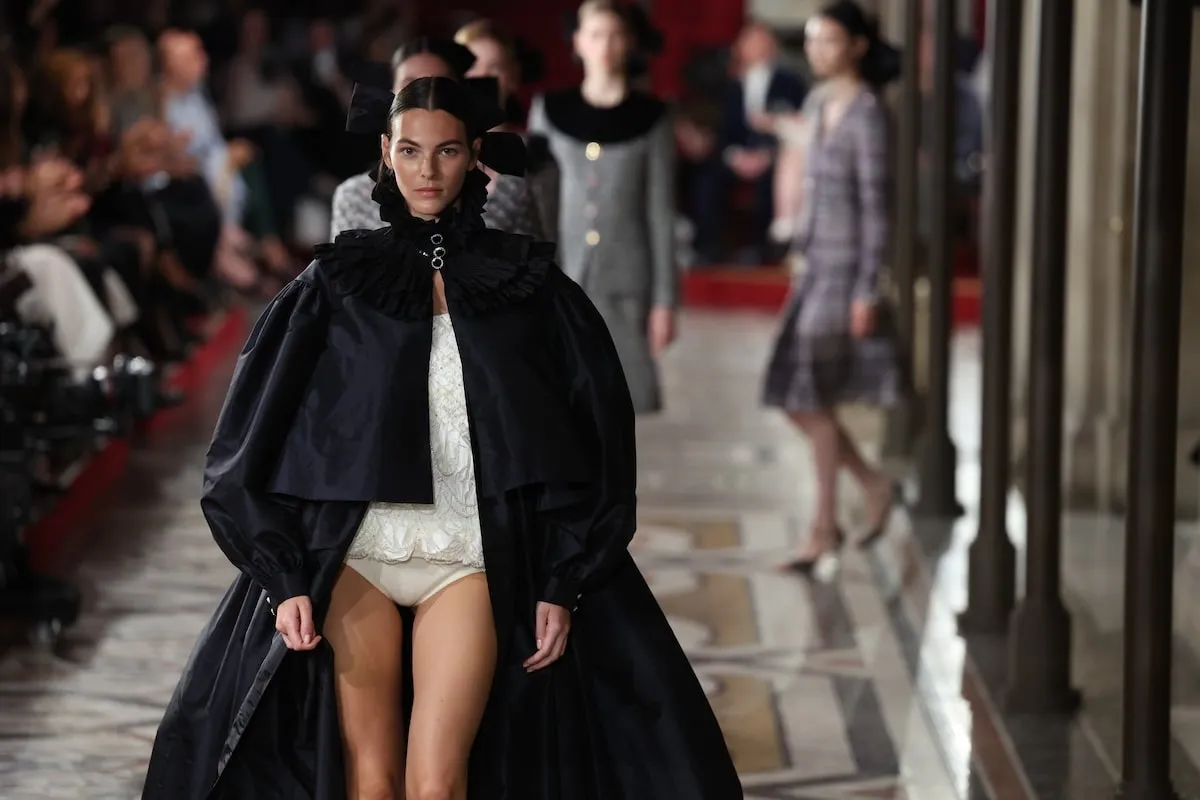 Wearing a black cape, Vittoria Ceretti walks the runway during the Chanel Haute Couture Fall/Winter 2024-2025 show