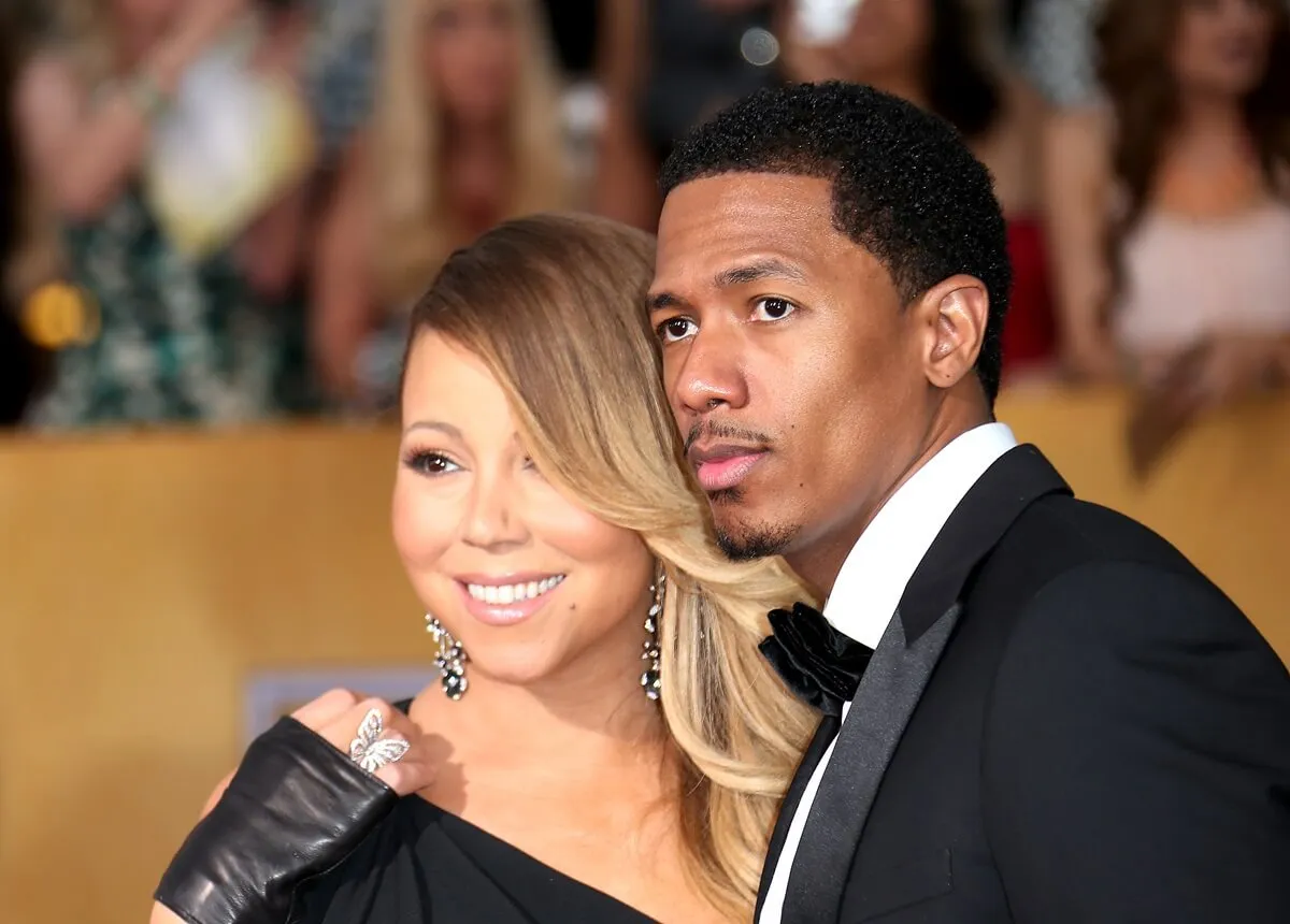 Nick Cannon and Mariah Carey posing in a suit and dress respectively at the 20th Annual Screen Actors Guild Awards.