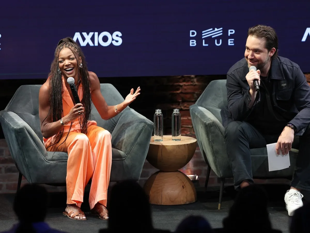 Wearing an orange outfit, Gabby Thomas speaks during a conversation with Alexis Ohanian