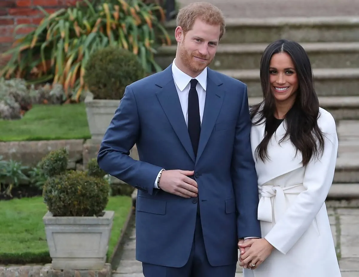 Prince Harry and Meghan Markle standing side-by-side in the Sunken Garden after their engagement announcement