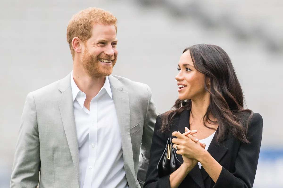 Prince Harry and Meghan Markle, who can garner a level of attention the royal family can't, per a commentator, stand next to each other