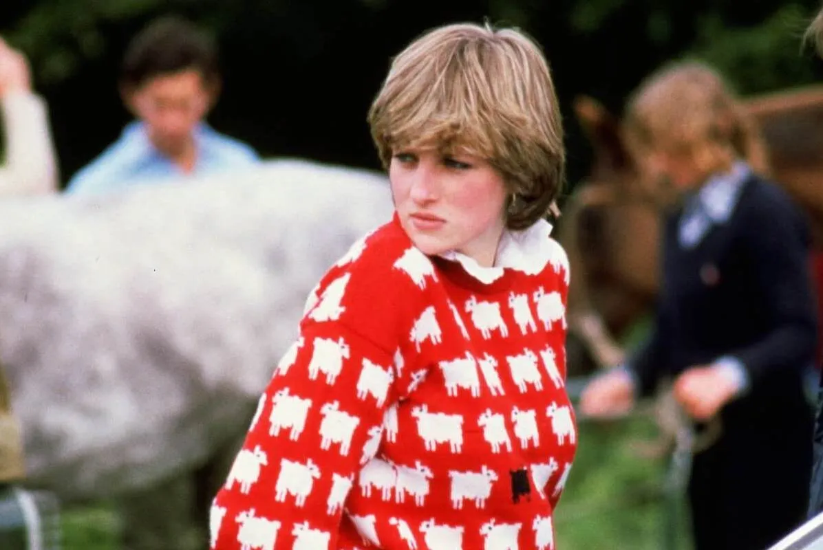 Princess Diana looks on wearing her iconic red sheep sweater, which is still available today.