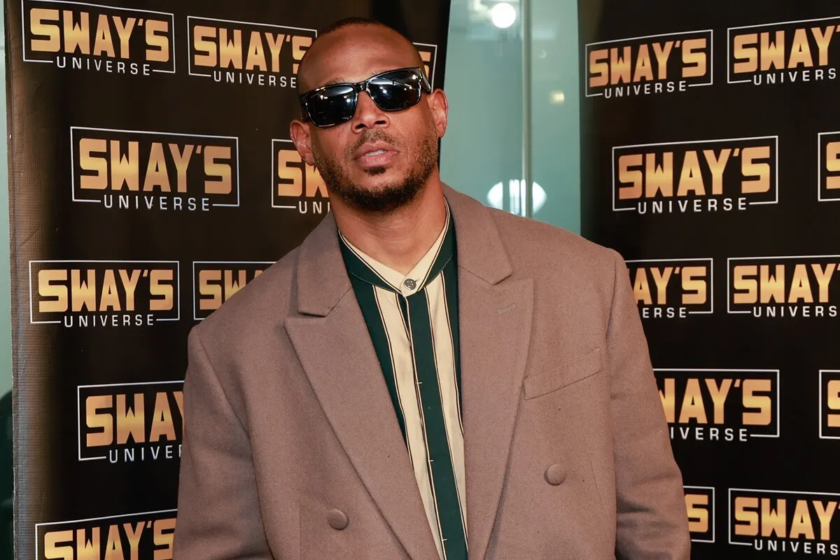 Marlon Wayans posing at Sirius XM in a brown trench coat.