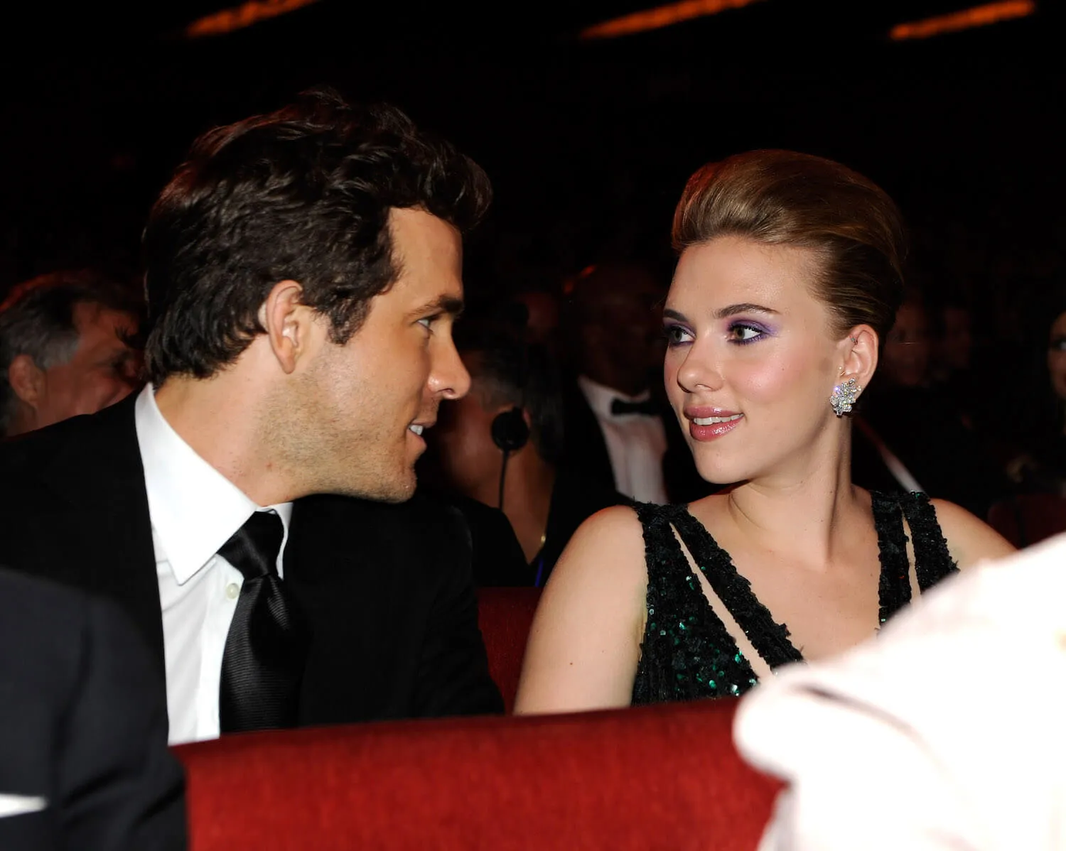 Ryan Reynolds and Scarlett Johansson sitting next to each other and looking at each other at the Tony Awards in 2010