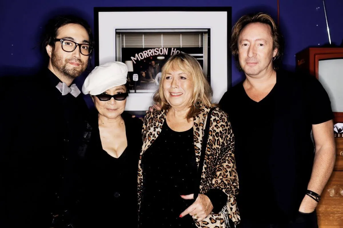 Sean Lennon, Yoko Ono, Cynthia Lennon, and Julian Lennon stand in front of a framed photograph.