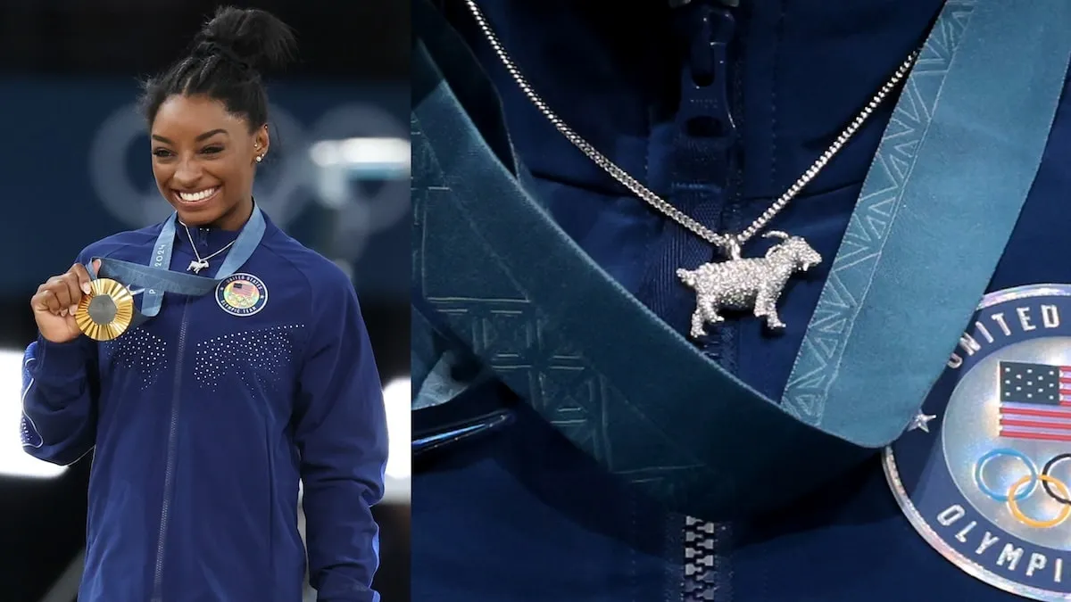 Gymnast Simone Biles smiles and holds up her gold medal after winning the Women's All-Around