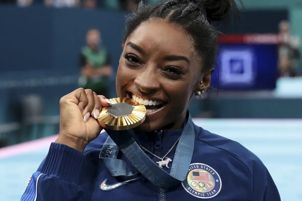 Gymnast Simone Biles bites her gold medal after winning the Women's All-Around