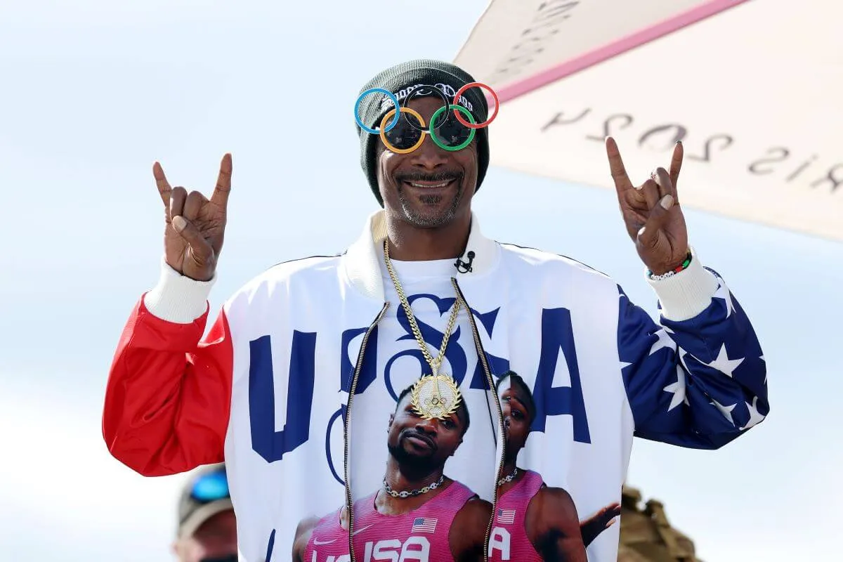 Snoop Dog wears a Team USA jacket and Olympic ring glasses.