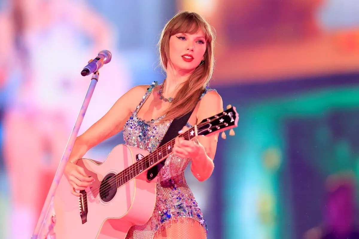 Taylor Swift wears a jeweled bodysuit and plays a guitar during her Eras Tour.