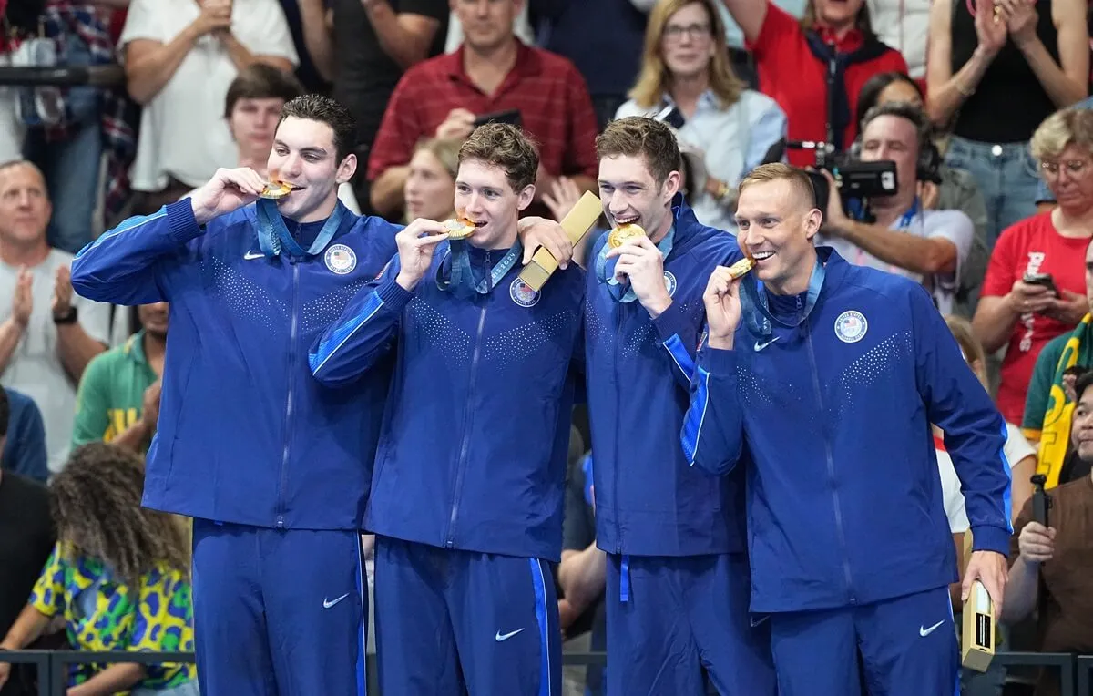 The U.S. relay team -- Jack Alexy, Chris Guiliano, Hunter Armstrong and Caeleb Dressel -- bite their gold medals