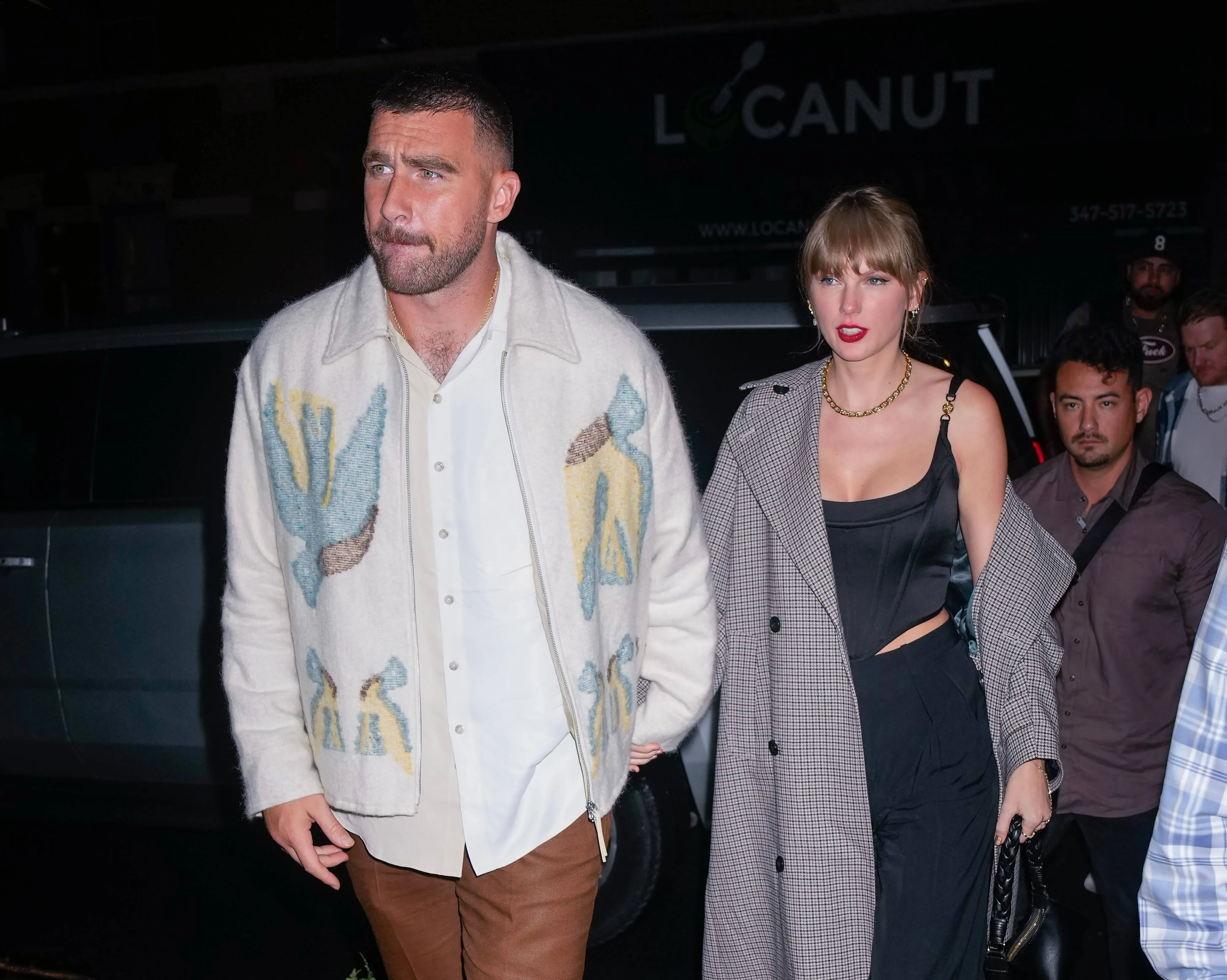 Travis Kelce and Taylor Swift walking hand in hand at night in 2023