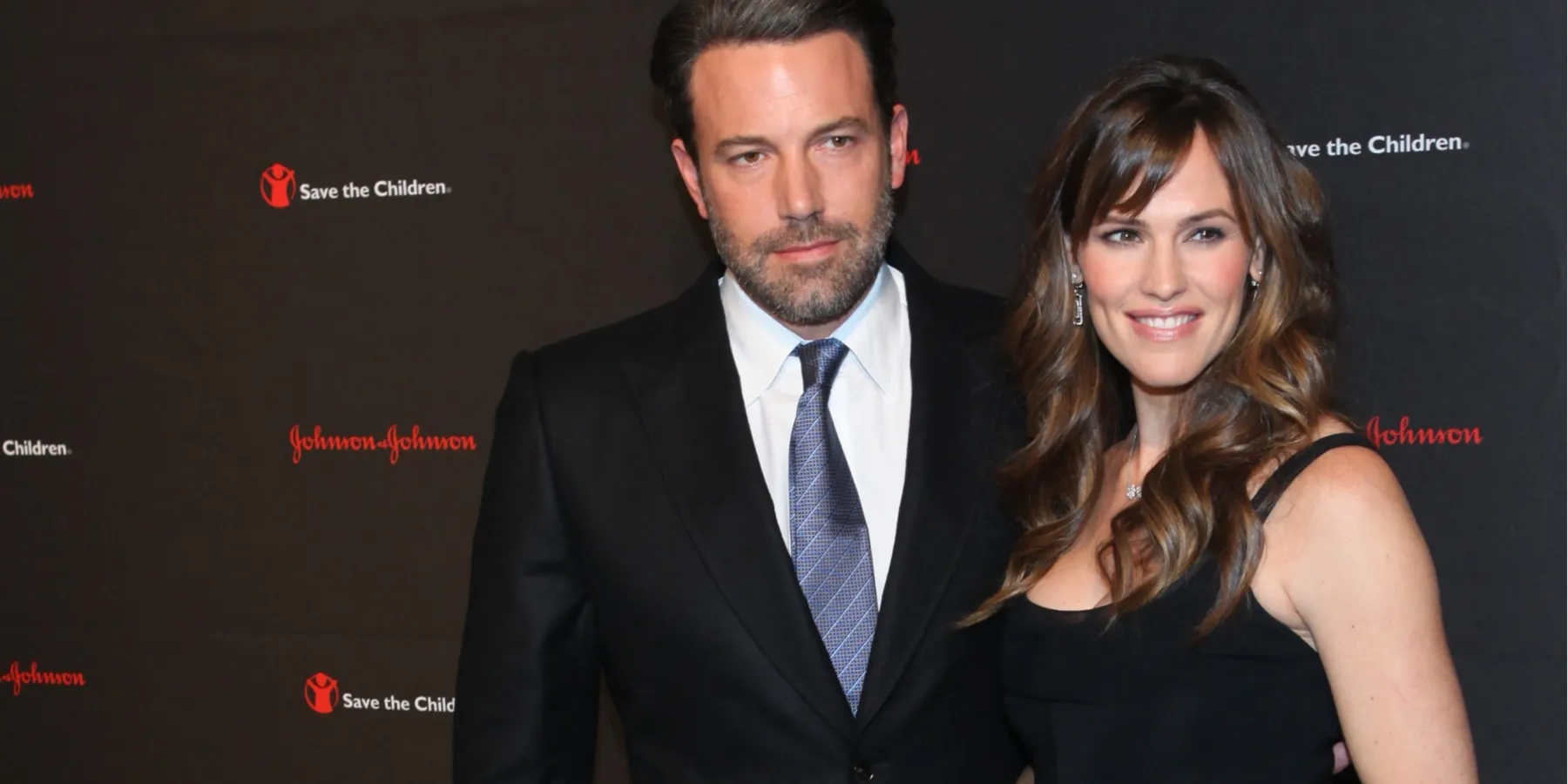 Ben Affleck and Jennifer Garner posing together while dressed up for a gala. Garner is smiling and Affleck is smirking.