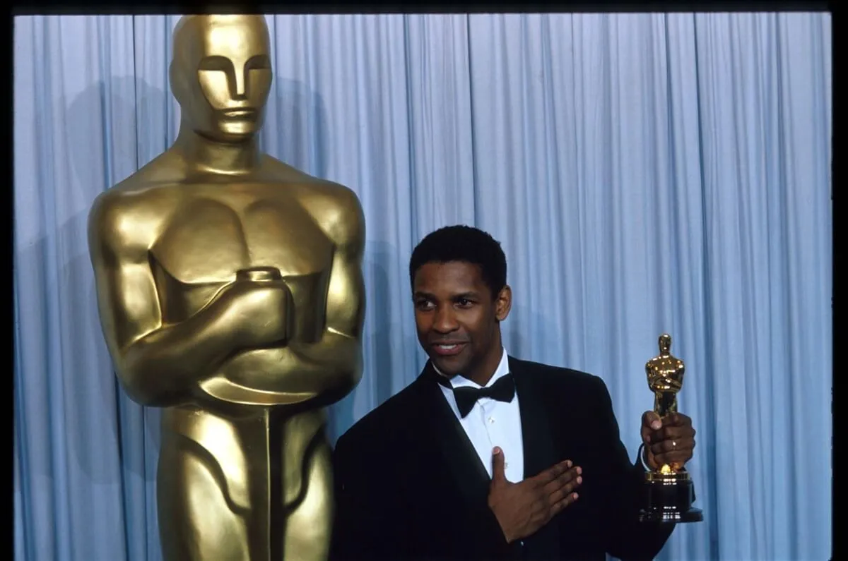 Denzel Washington posing with an Oscar trophy.