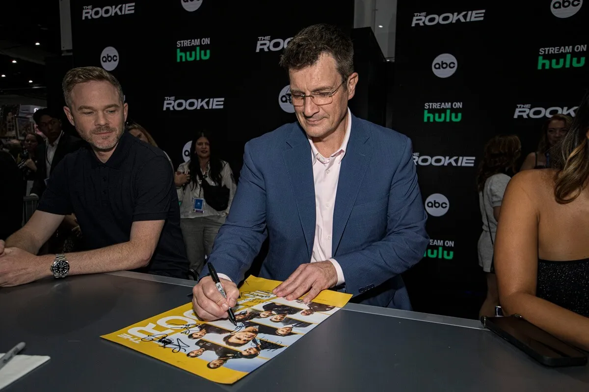 Nathan Fillion at Comic Con signing autographs.