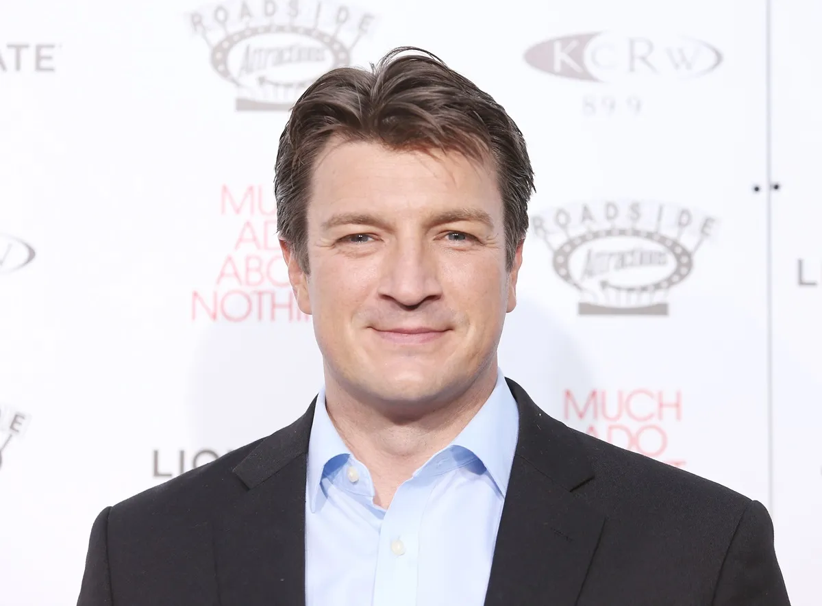 Nathan Fillion posing at the premiere of 'Much Ado About Nothing' in a suit.