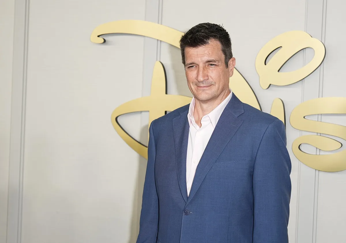 Nathan Fillion posing in a blue suit at a Disney event.