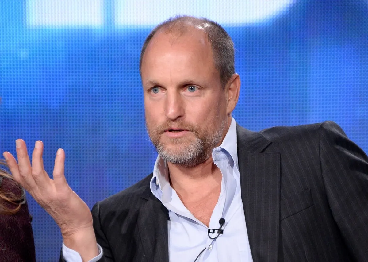 Woody Harrelson talking at a 'True Detective' panel in a suit.