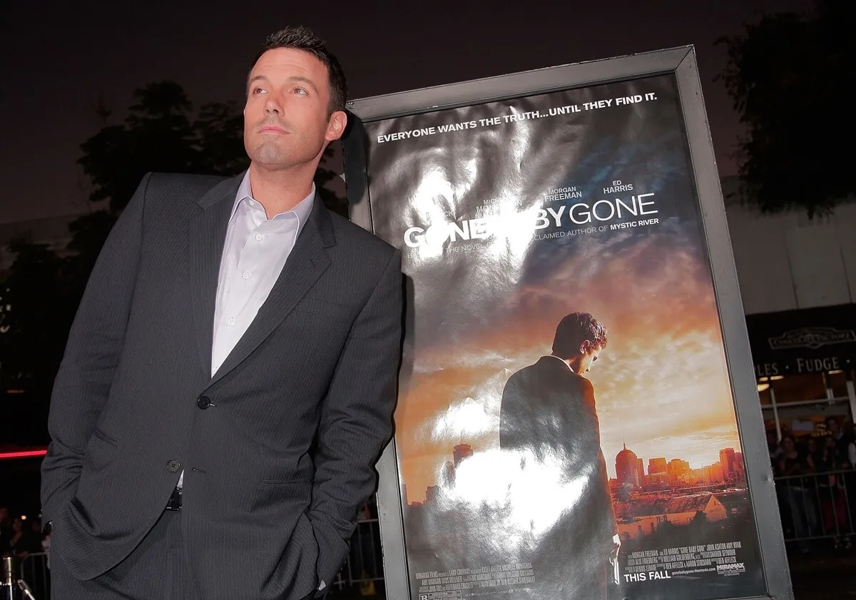 Ben Affleck posing in front of a movie poster for 'Gone Baby' Gone' at the film's premiere.