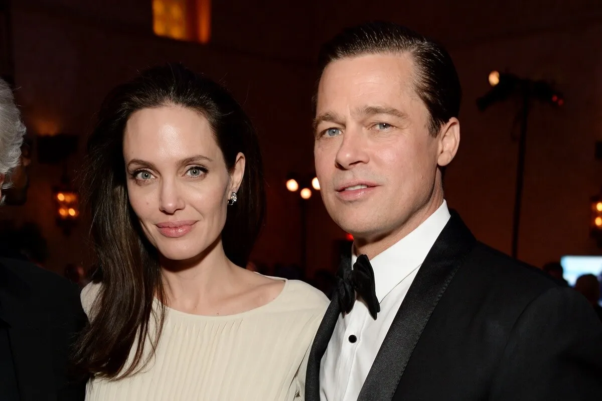 Brad Pitt in a suit posing next to Angelina Jolie in a white shirt at the premiere of 'By the Sea'.