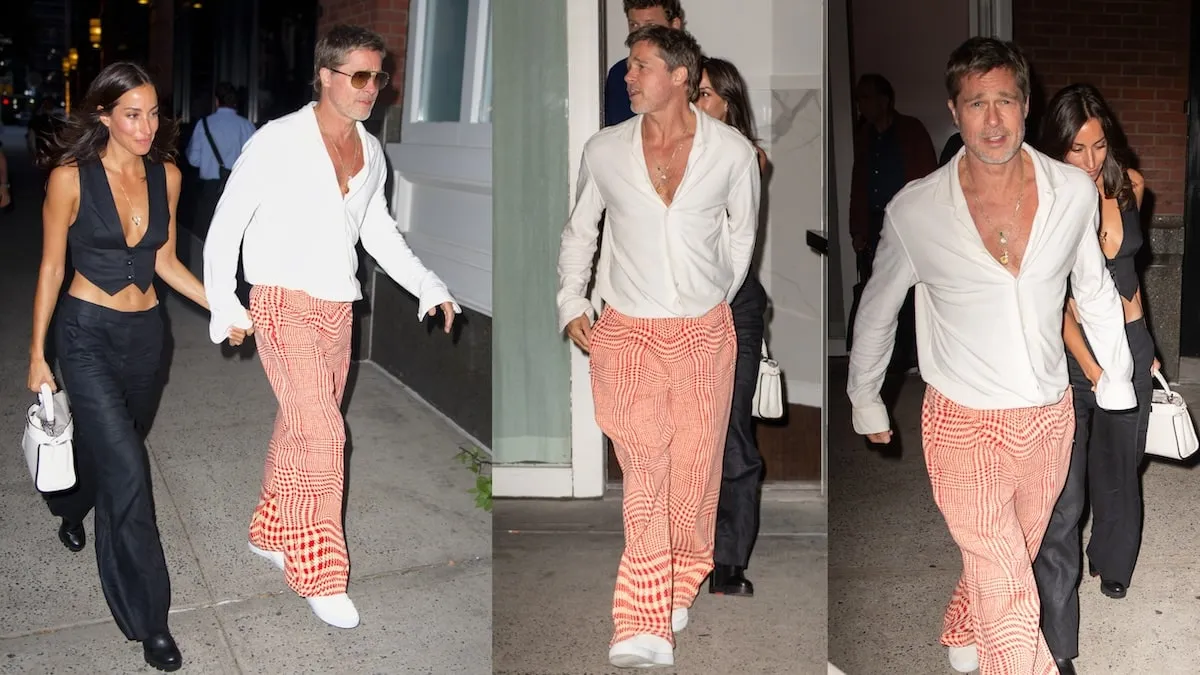 Dating couple Ines de Ramon and Brad Pitt walk on an NYC street wearing a black pantsuit and orange respectively