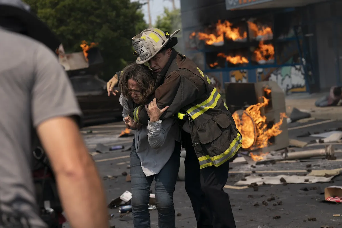 Firefighter shielding a woman in front of a fire in the 'Chicago Fire' Season 13 premier