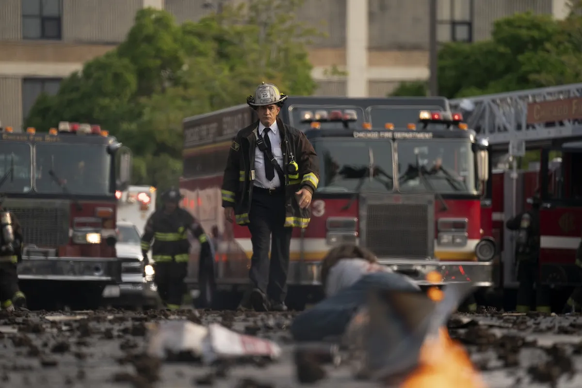 Man wearing a fireman's hat walking in front of a firetruck