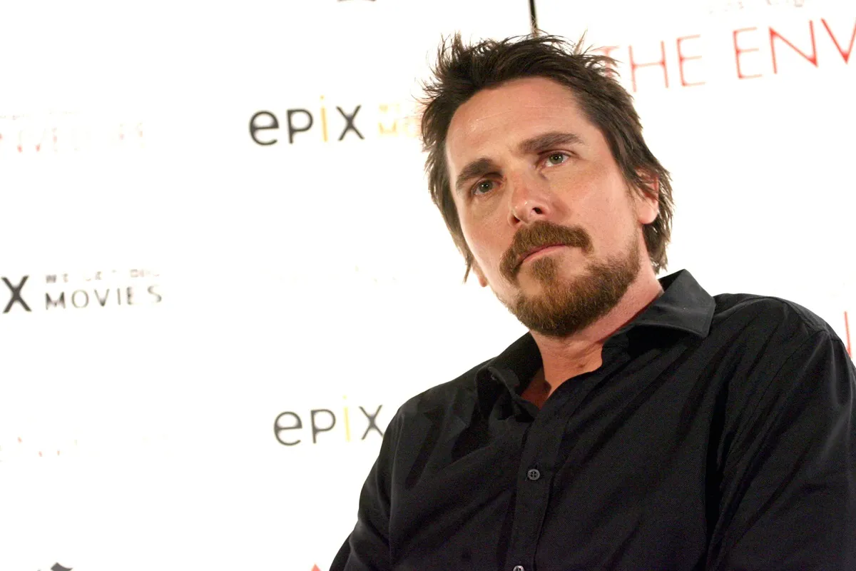 Christian Bale sitting down in a black shirt at a screening for the movie 'Out of the Furnace'.