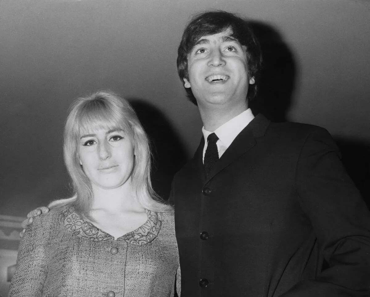 A black and white picture of Cynthia Lennon standing next to John Lennon. He wears a suit.