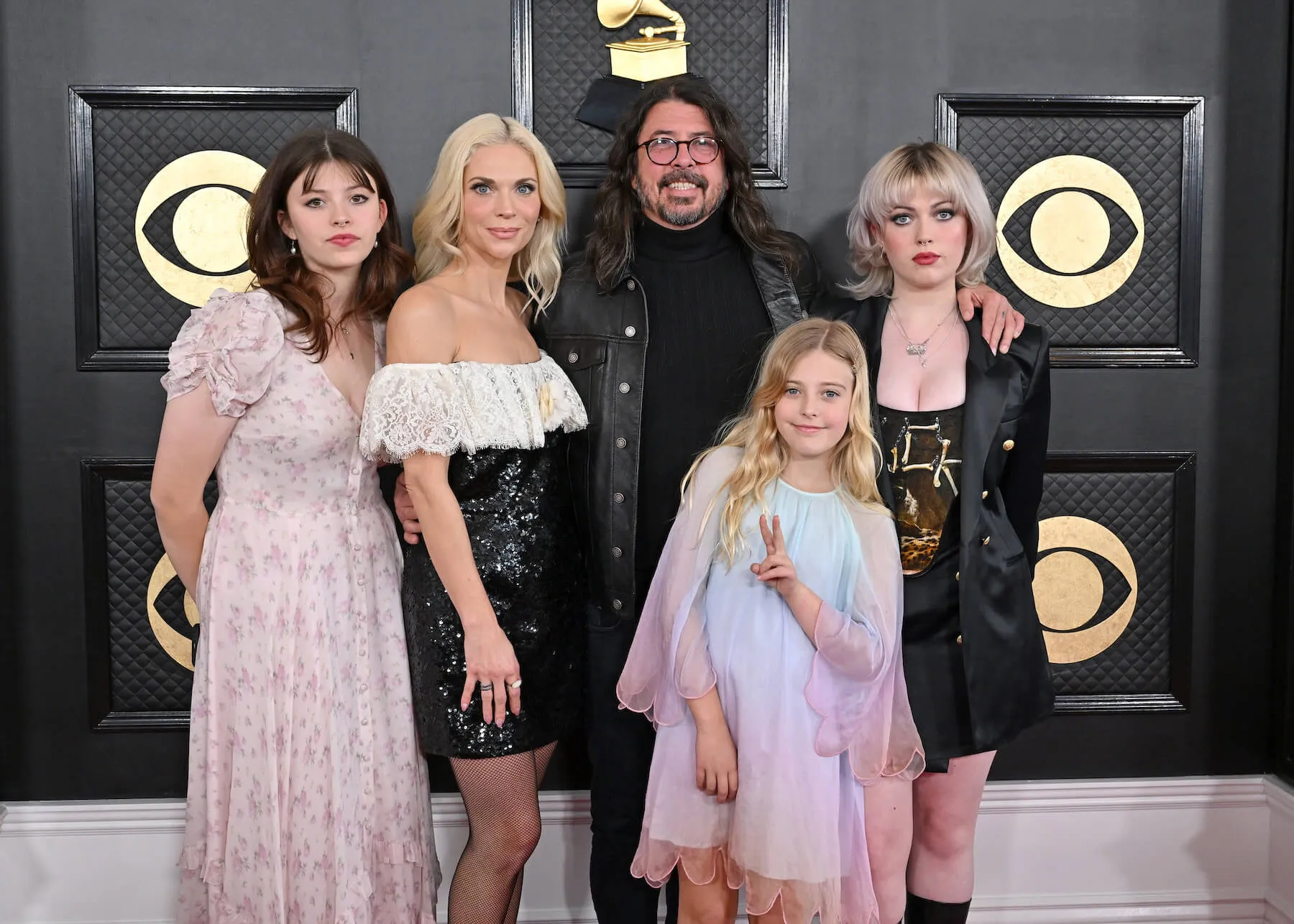 Dave Grohl smiling and posing with his daughters and wife at the Grammys in 2023