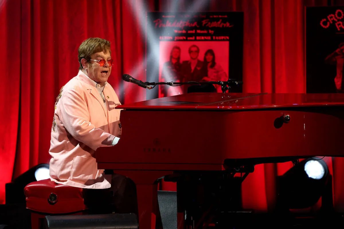 Elton John, who called Chappell Roan 11 times in five days, sits at a piano.