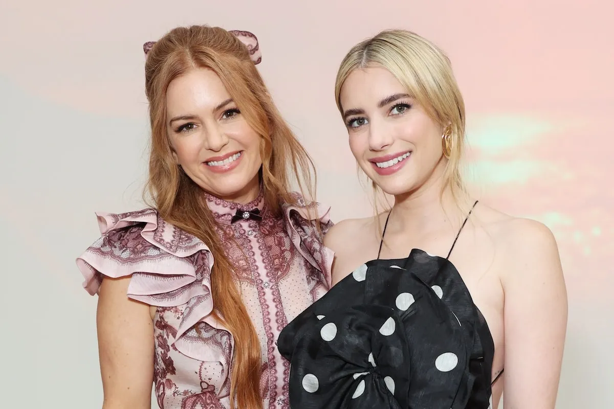 Actors Isla Fisher and Emma Roberts stand together to take a photo at the Zimmermann show during Paris Fashion Week