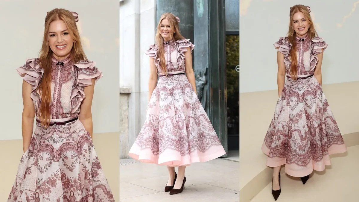 Wearing a pink floral ruffly dress, Isla Fisher poses for photos at the Zimmermann show during Paris Fashion Week