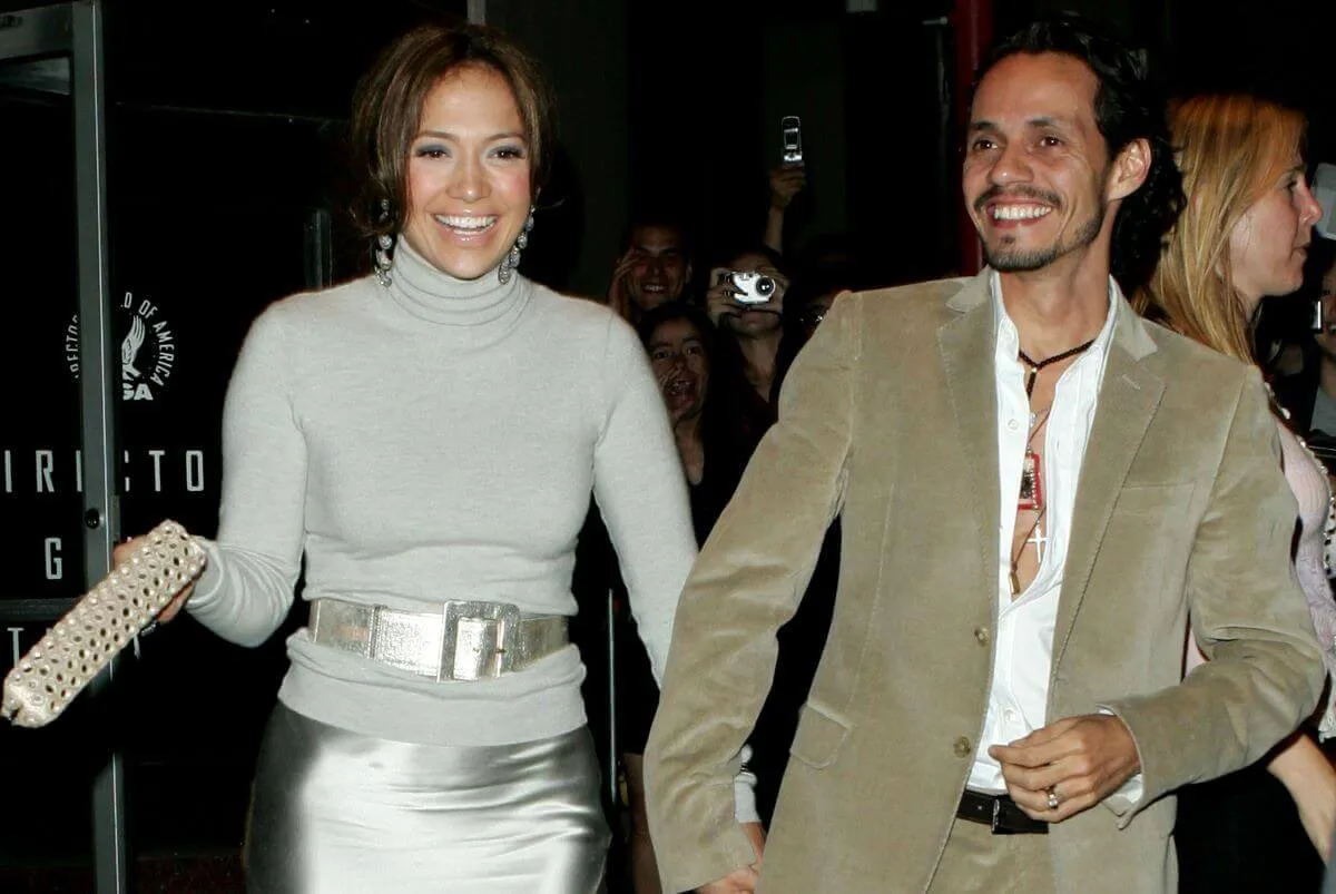 Jennifer Lopez wears a silver skirt and sweater and walks with Marc Anthony. He wears a tan suit.