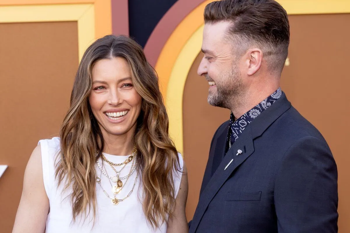 Justin Timberlake wears a blue suit and turns toward Jessica Biel, who wears a white shirt.