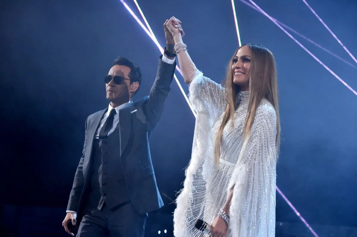 Marc Anthony and Jennifer Lopez hold hands and lift their arms in the air.