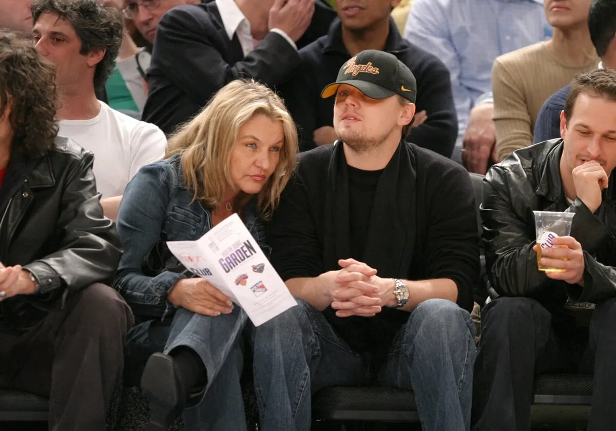 Leonardo DiCaprio sitting down next to his Mom Irmin DiCaprio at a Knicks game.