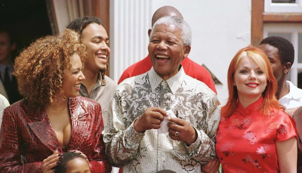 Nelson Mandela laughs while standing in between Mel B and Geri Halliwell of the Spice Girls.