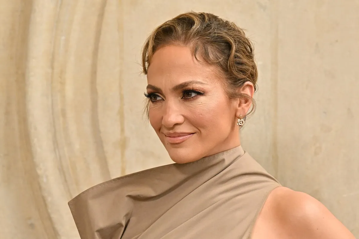 Jennifer Lopez posing while wearing a light brown dress at Fashion Week.