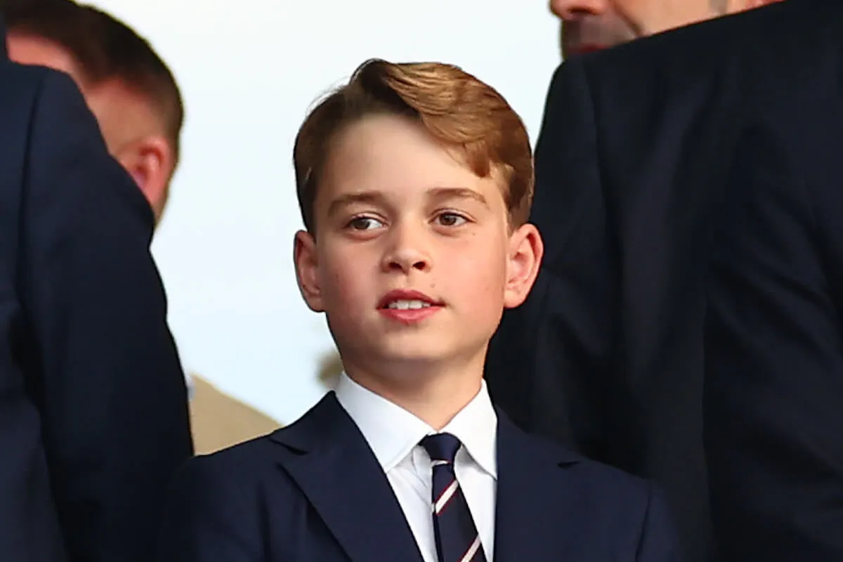 Prince George, who is growing up quickly as Prince William and Kate Middleton prepare him to be king, looks on wearing a suit and tie.