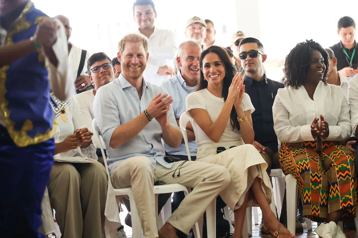 Prince Harry and Meghan Markle smiling and clapping