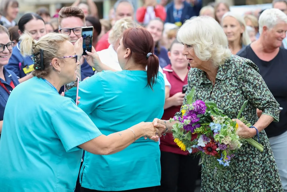 Queen Camilla shakes hands with staff and well-wishers during her visit to the Dyson Cancer Center