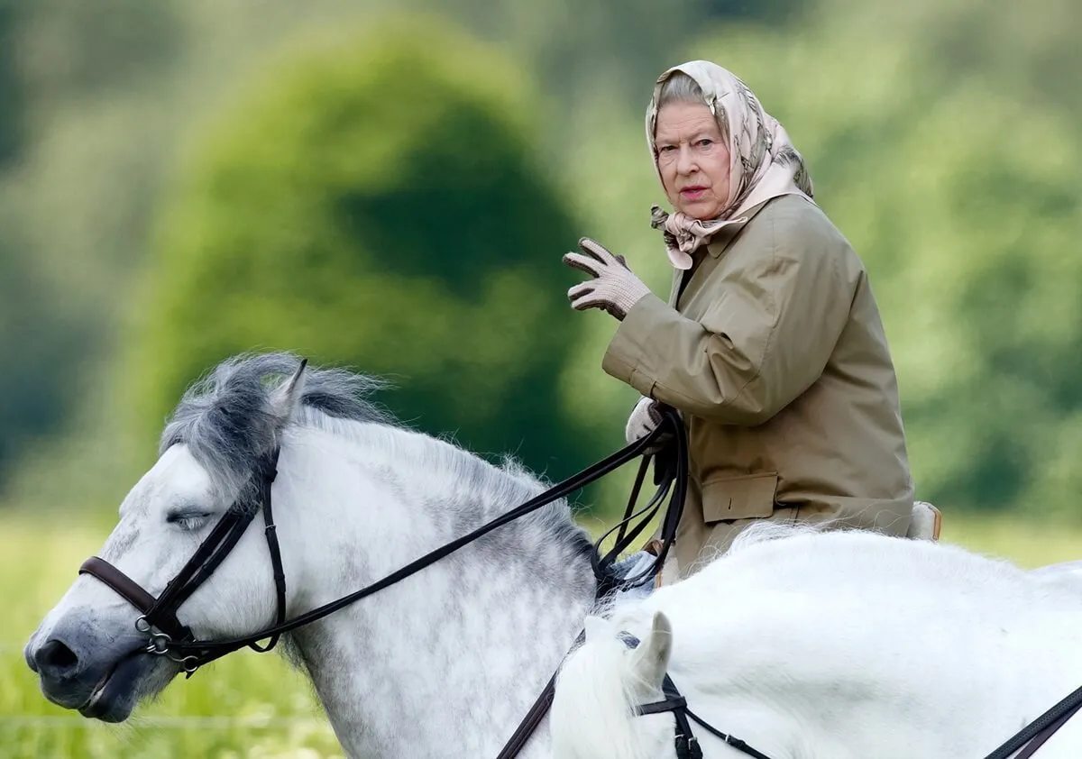 Queen Elizabeth II riding a horse on the grounds of Windsor Castle