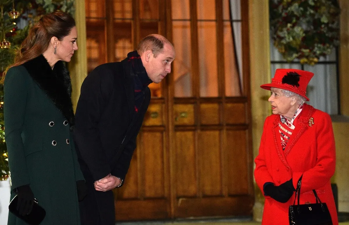 Queen Elizabeth II speaks with Prince William and Kate Middleton as they wait to thank local volunteers who continued essential work during the coronavirus pandemic