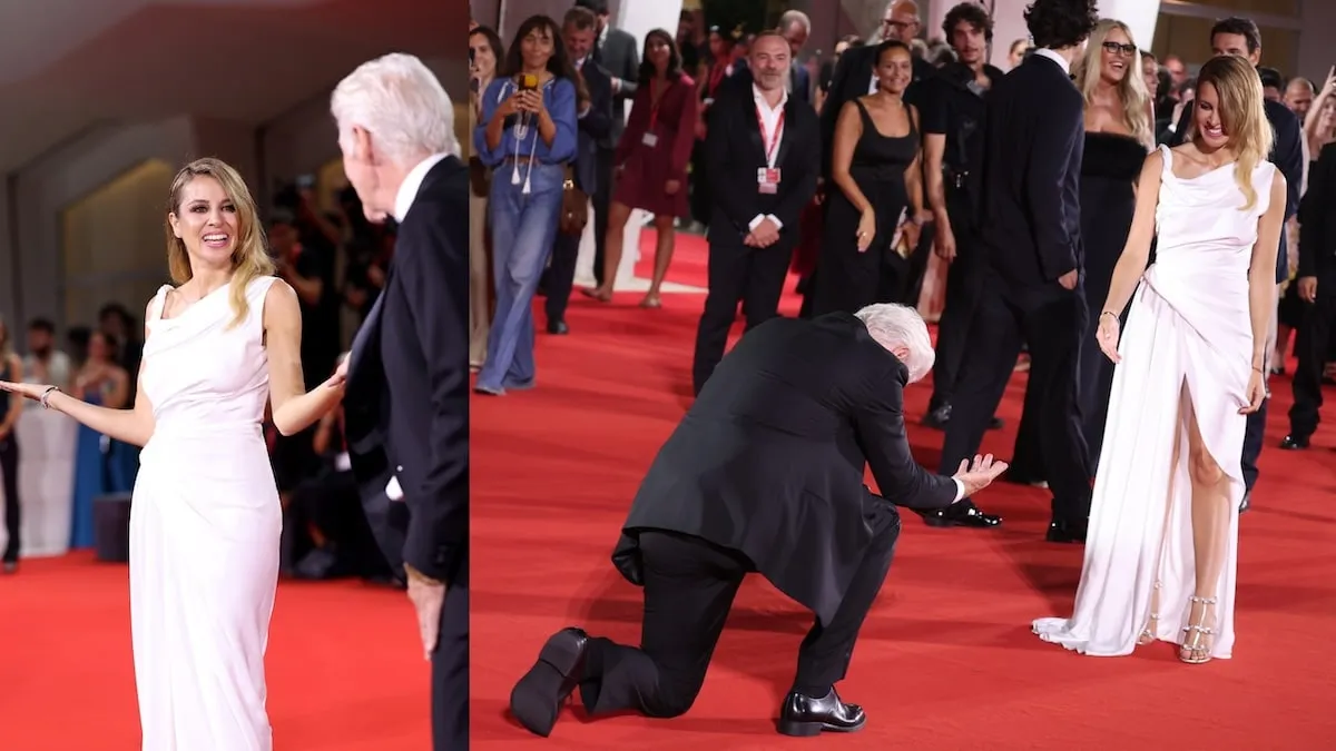 Wearing a tuxedo, Richard Gere kneels in front of his his wife Alejandra Silva as they attend the Filming Italy Venice Award red carpet