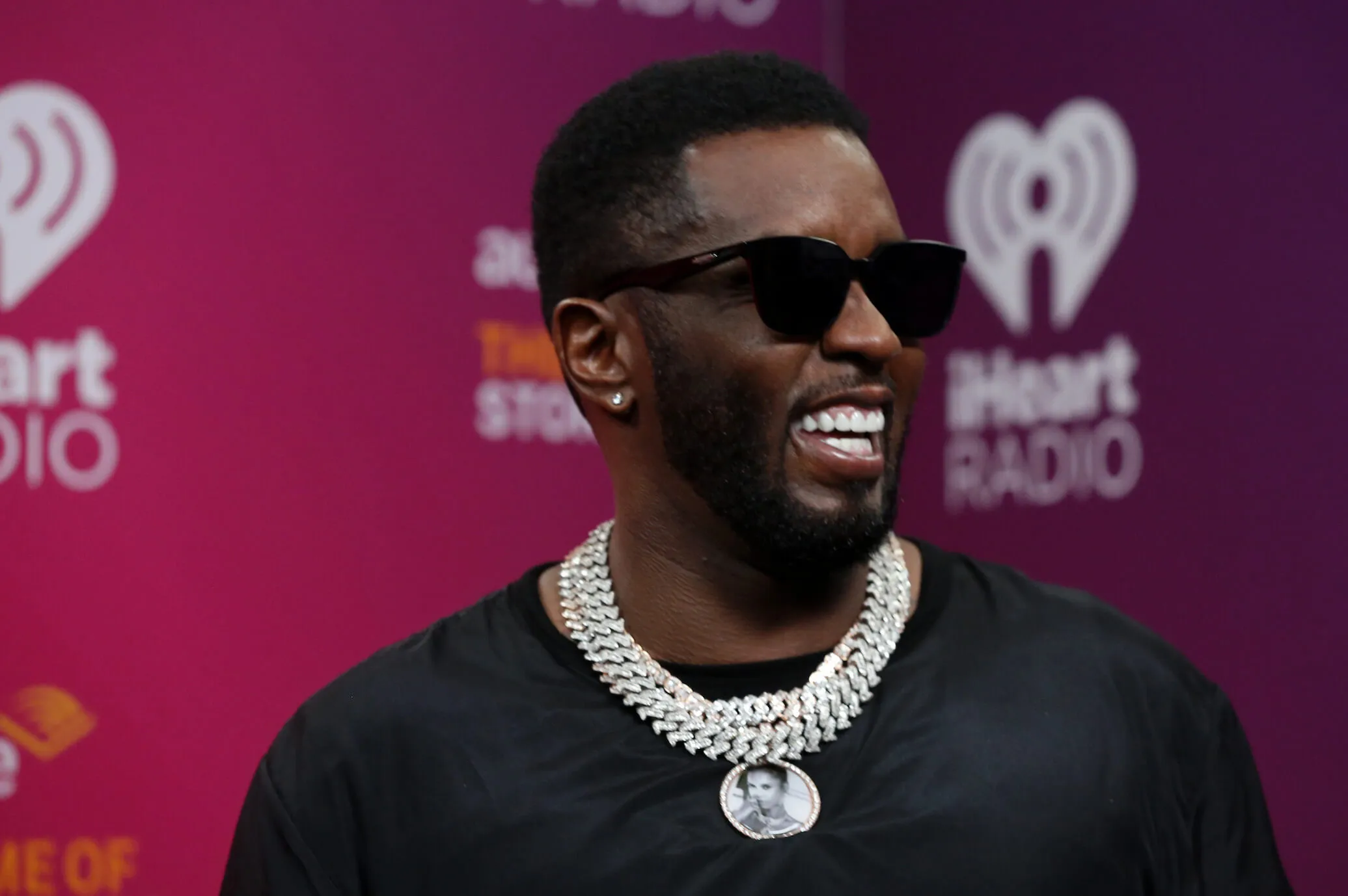 Sean 'Diddy' Combs smiling while at the 2022 iHeartRadio Music Festival. He's wearing a black shirt and sunglasses.