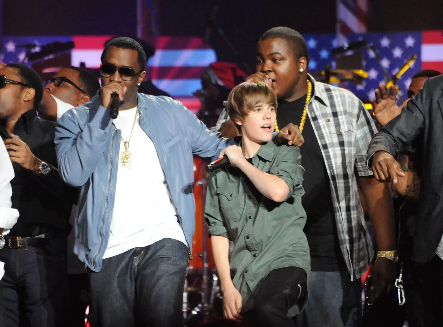 Sean 'Diddy' Combs and Justin Bieber singing on stage with other performers for a benefit concert in 2010